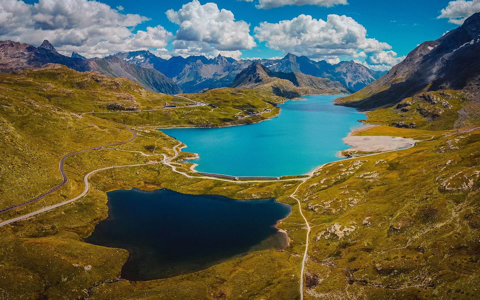 An aerial view of Lago Bianco and Lago Nero on the Bernina Pass with mountain ranges behind.