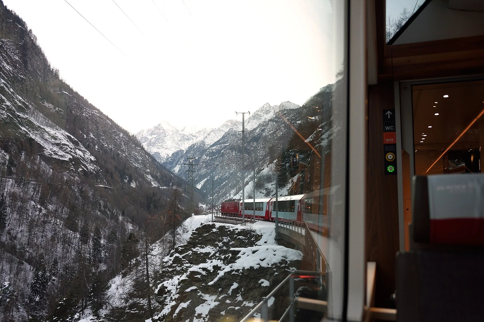 The view from a Glacier Express window towards Zermatt, with the train curving along a steep valley.