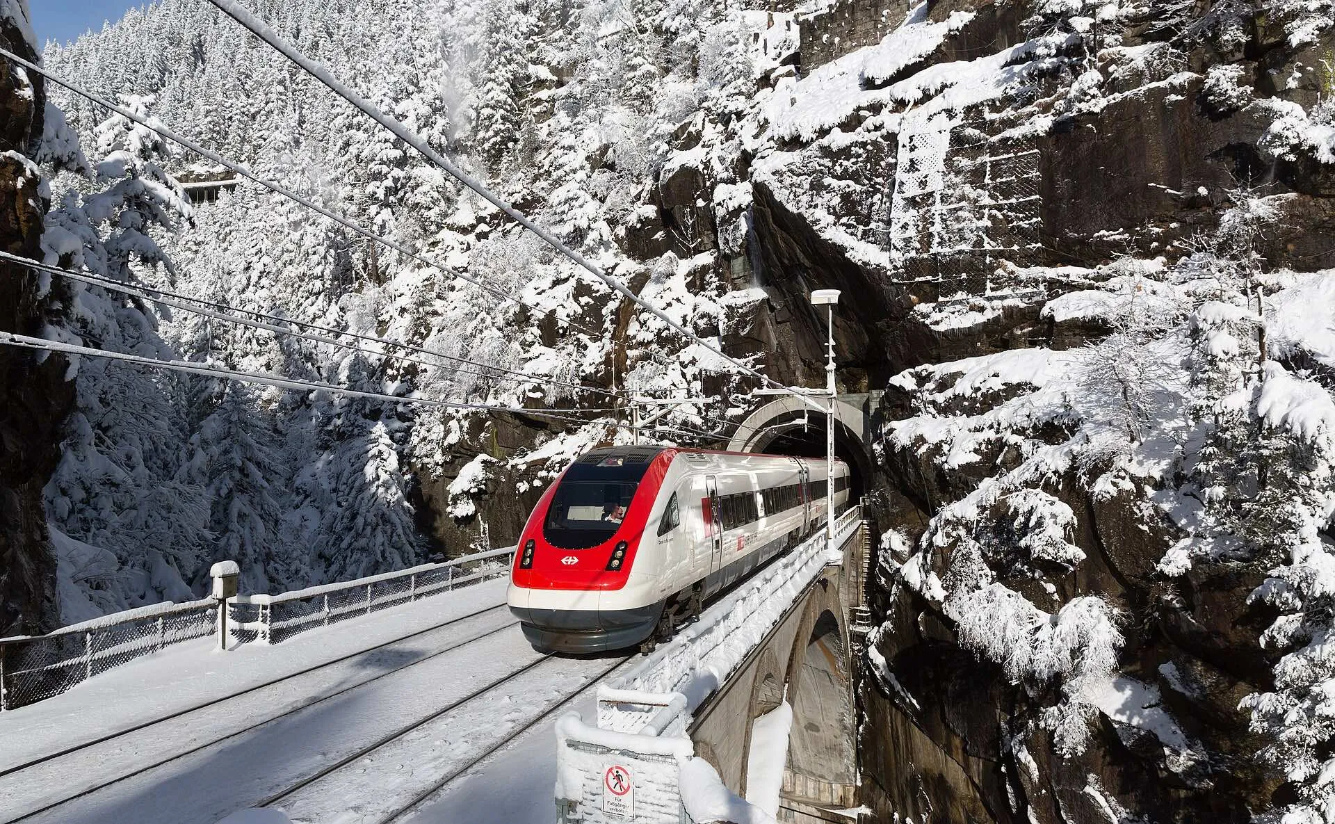 A white SBB tilting train crossing the upper Meienreuss bridge near Wassen in fresh snow.