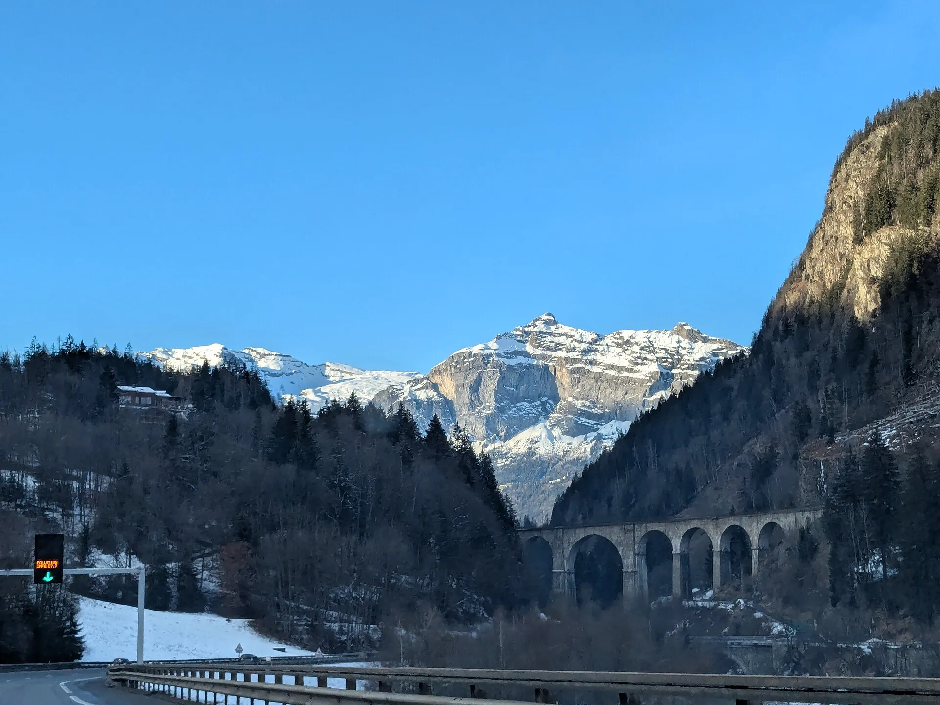 The stone arches of the Sainte-Marie viaduct near Les Houches in winter with snowy peaks beyond.